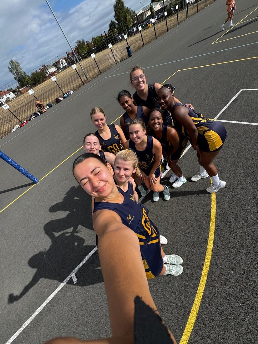Eagles players striking a playful team pose under a netball post