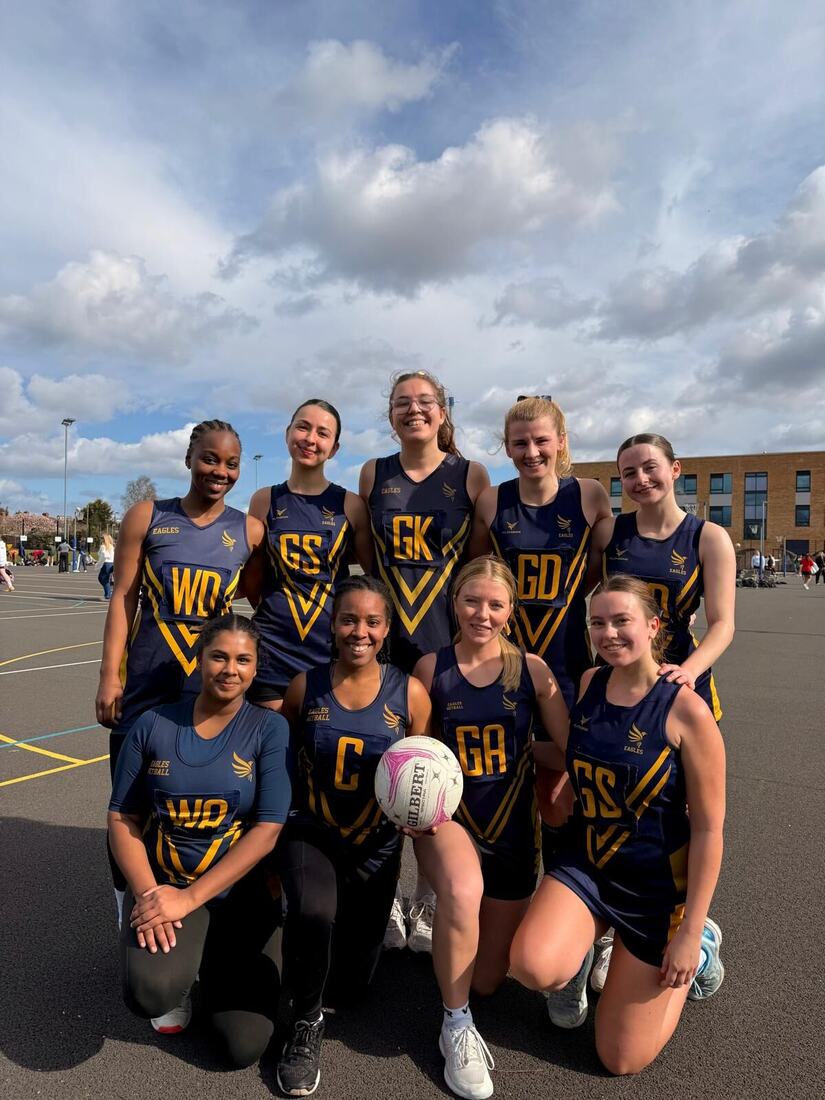 Eagles players in navy and gold bibbed kit on a sunny outdoor court