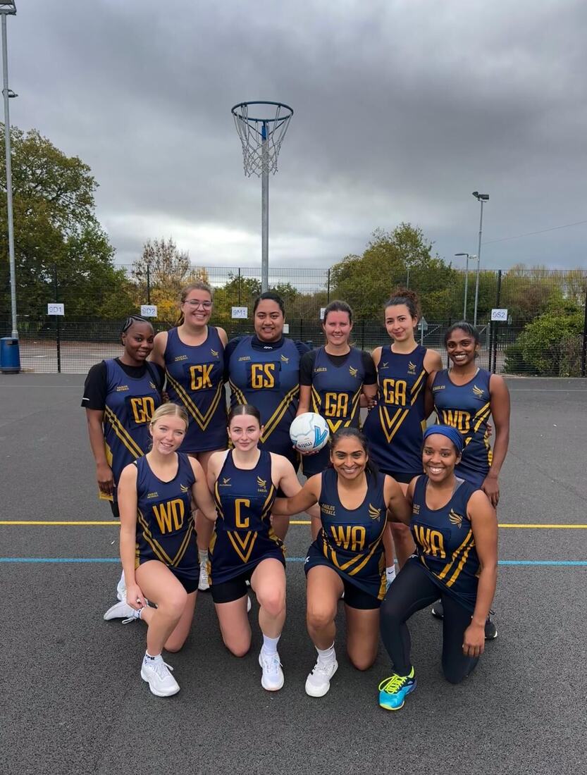 Eagles squad lined up beneath a netball post with a match ball