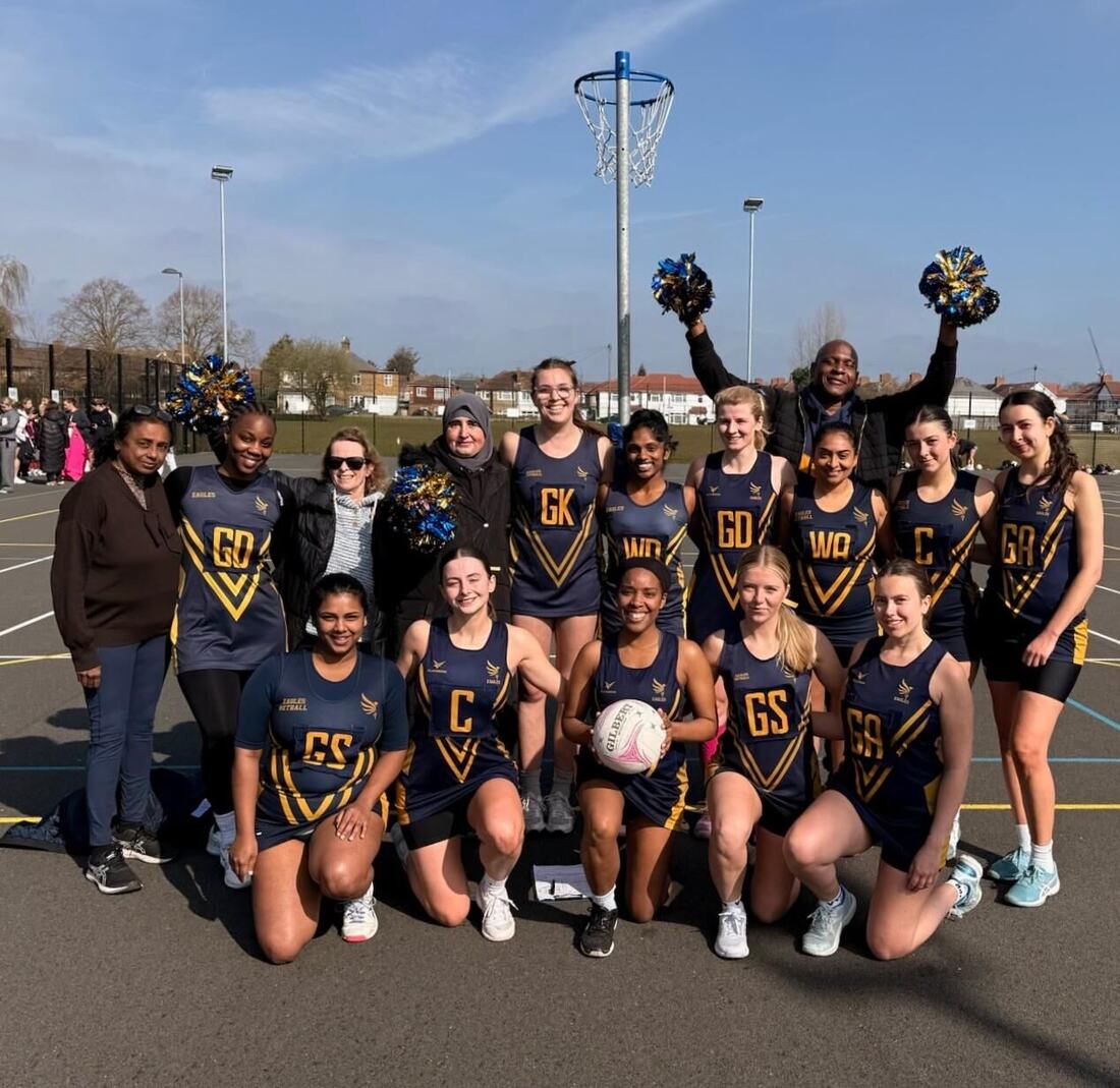 Eagles players in navy and gold kit celebrating together on an outdoor court, with a coach cheering behind them