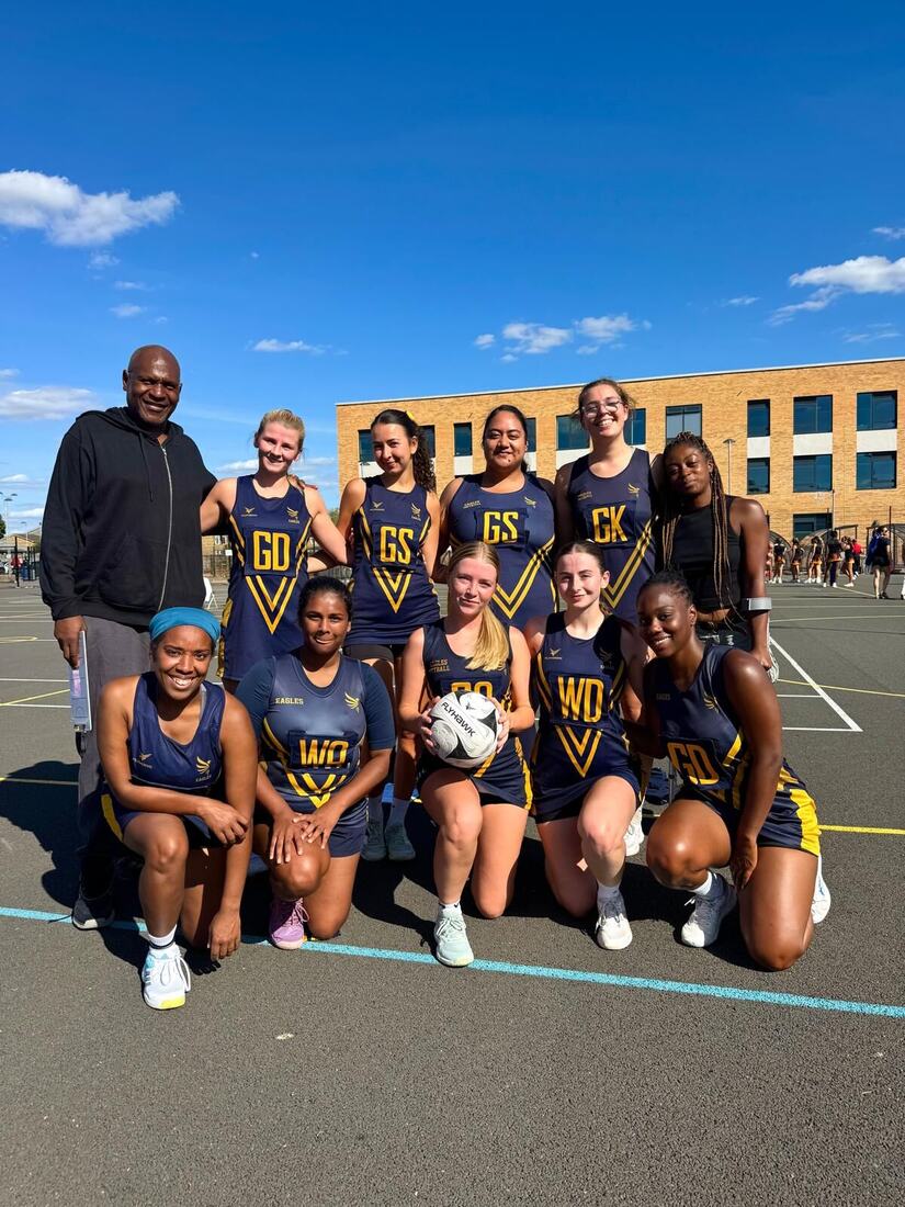 Eagles squad with their coach on an outdoor court in front of a school building