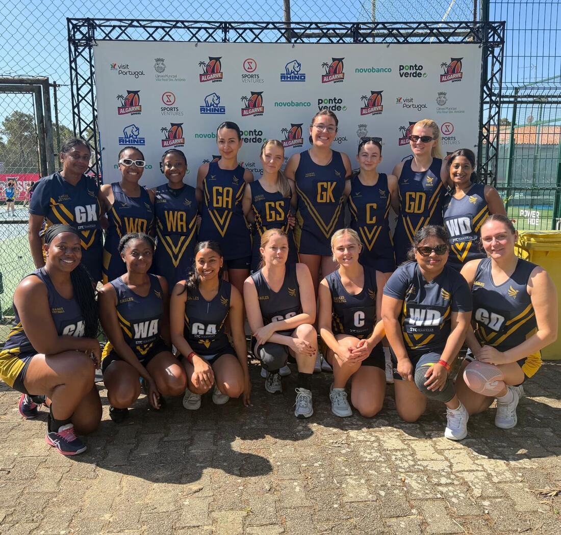 A large Eagles squad posing in front of a tournament sponsor board